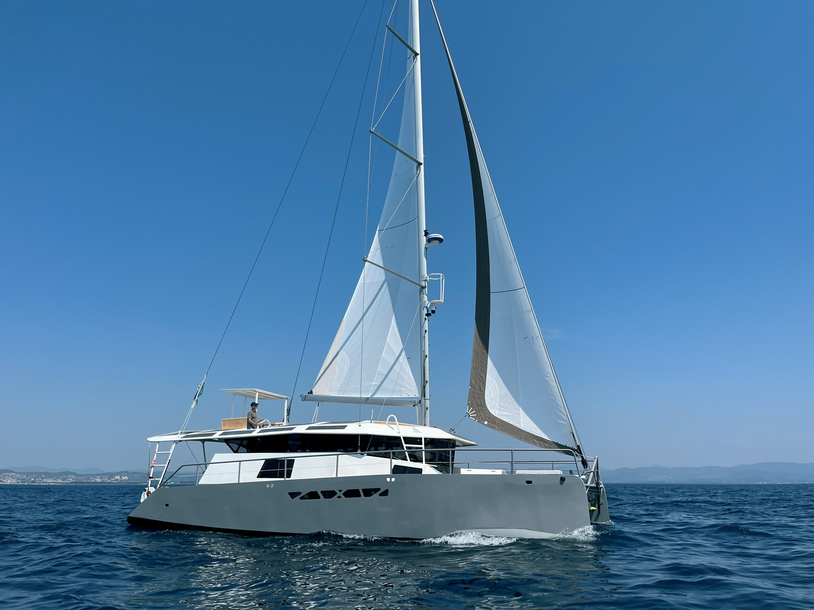 On distingue bien les rostres de la coque qui apporte un surplus de longueur à la flottaison. Le mat, très haut, compense l’absence de recouvrement du foc et l’étroitesse de la grand-voile sur enrouleur (pas de rond de chute).