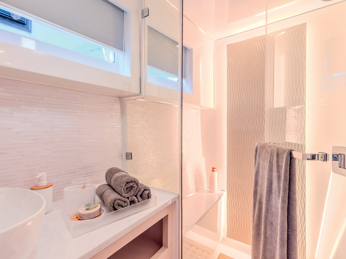 La suite Propriétaire occupe la totalité de la coque bâbord avec le lit à l’arrière, la salle de bains longitudinale à l’avant et l’espace de vie entre les deux. Les nombreux volumes de rangement et penderies garantissent le confort lors des croisières de longue durée.  Le style et les caractéristiques personnalisées, comme le carrelage de la salle de bains, confèrent au Cora 48 un caractère unique.