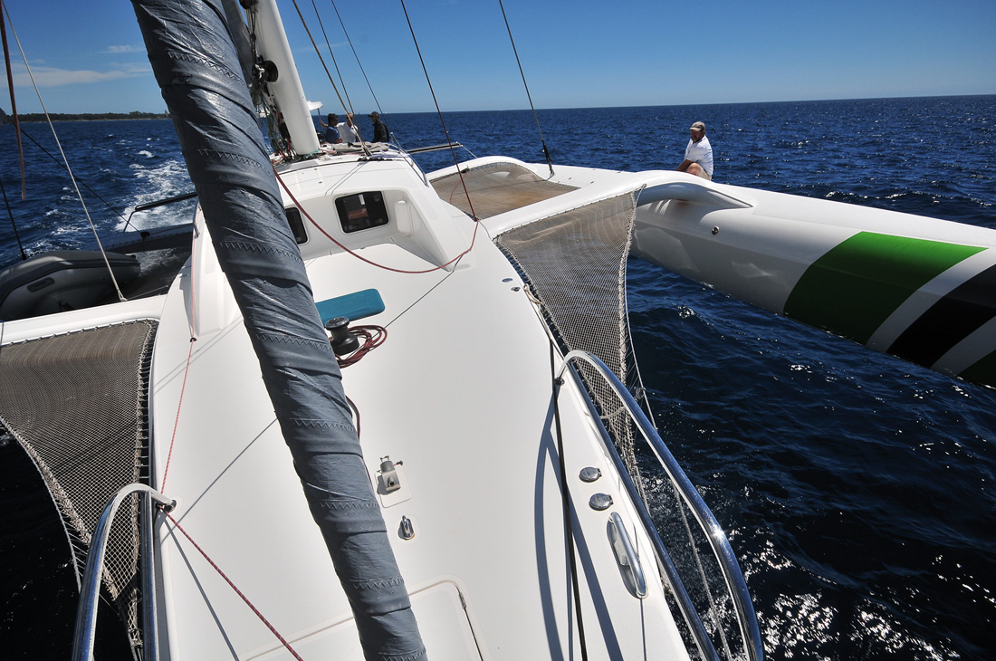 Dièdre dynamique en fonctionnement, le flotteur au vent bien dégagé de l'eau. Rapido taille sa route à vive allure sur une mer plate et un vent inférieur à 12 nœuds. La plage avant et le poste à mouillage sont bien ceux d'un multicoque de croisière.
