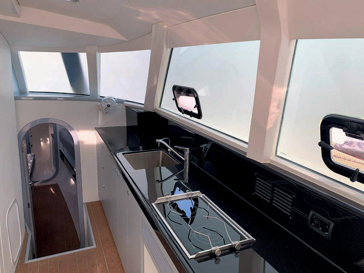 Sur tribord, une longue cuisine avec un plan de travail et  des tiroirs en carbone.  Tout l’équipement nécessaire  est bien en place.