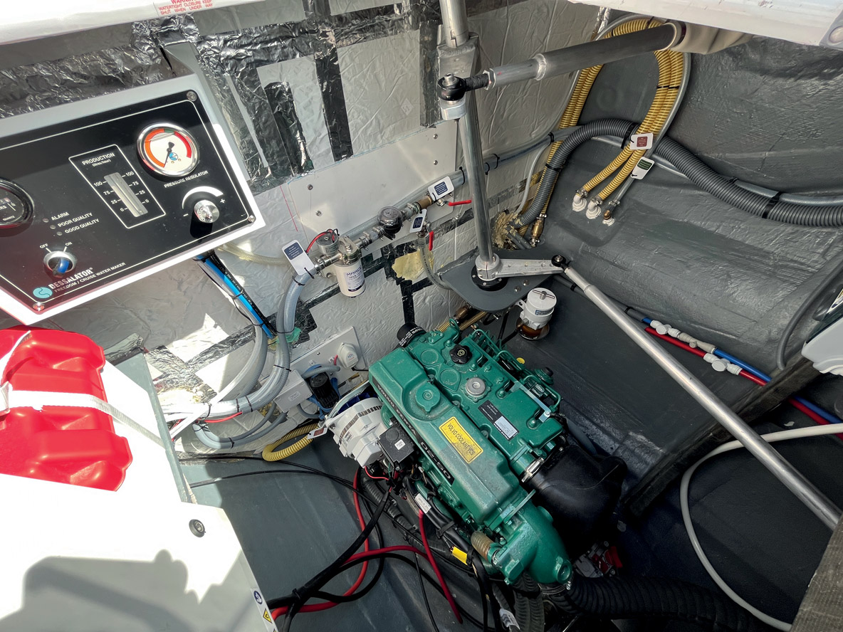 La cale moteur est assez vaste pour assurer un entretien dans de bonnes conditions sur le 50 CV Volvo. On aperçoit la tringle qui relie la barre franche au système de barre à roue sur l’autre bord.