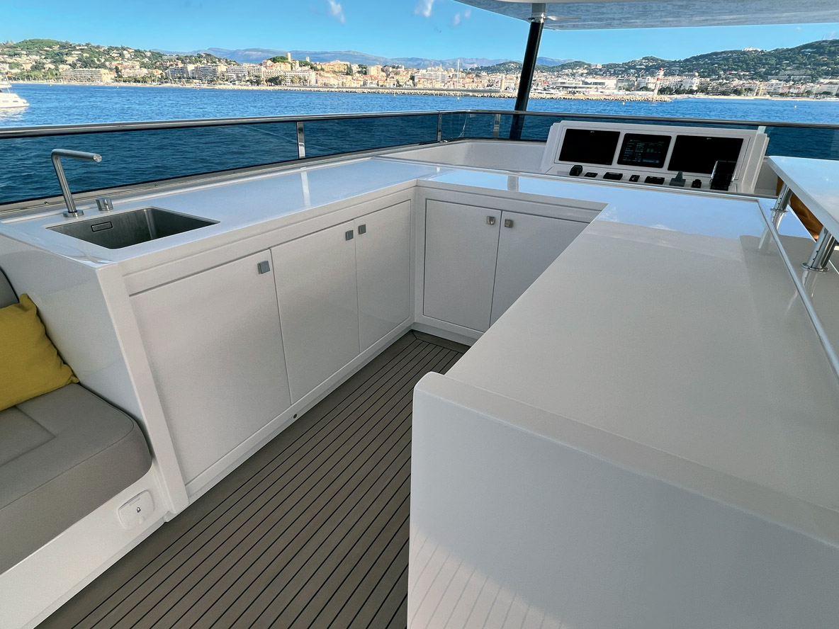 The flybridge, with its impressive surface area, features large benches and a galley with a counter.