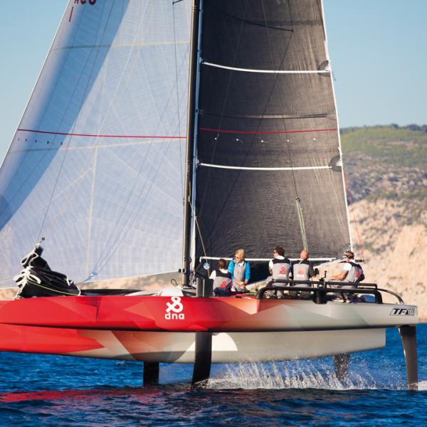 L'équipage (4 ou 5 équipiers) en configuration de vol : un barreur, un régleur de GV, un régleur de voile d'avant et un grinder dans la coque centrale.