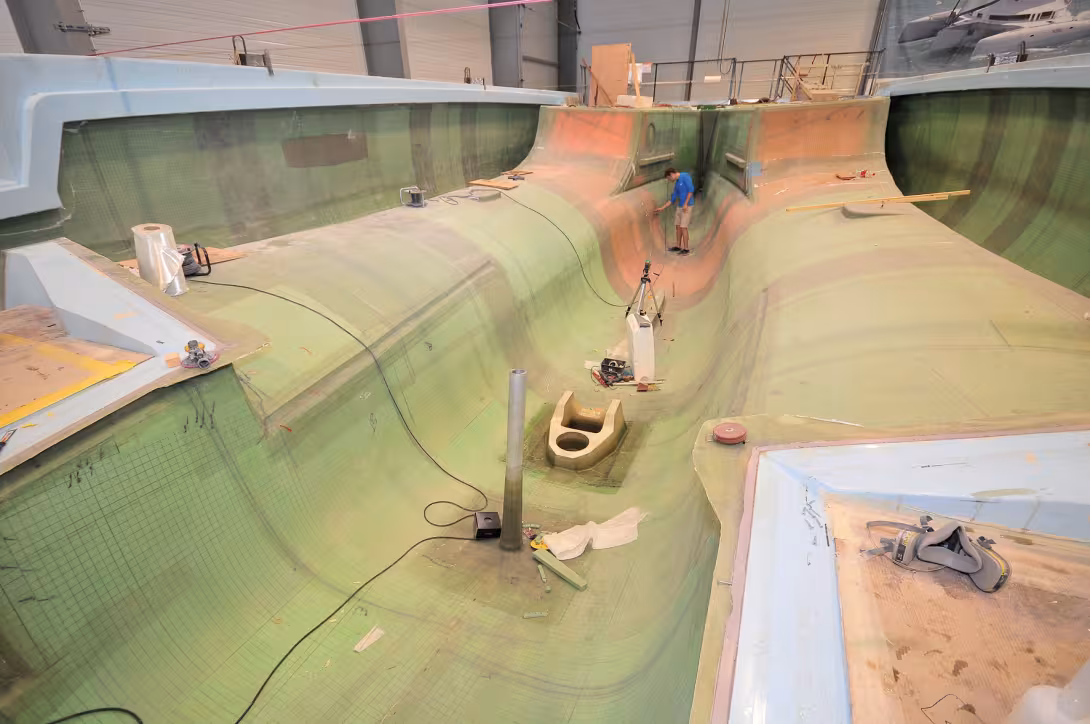 Un Neel 51 en fin de phase composite infusion, le moule en 3 parties inclut la coque centrale et les demi-coques intérieures, les demi-coques extérieures sont visibles ; les cloisons maîtresses traversantes et des cloisons secondaires sont corniérées